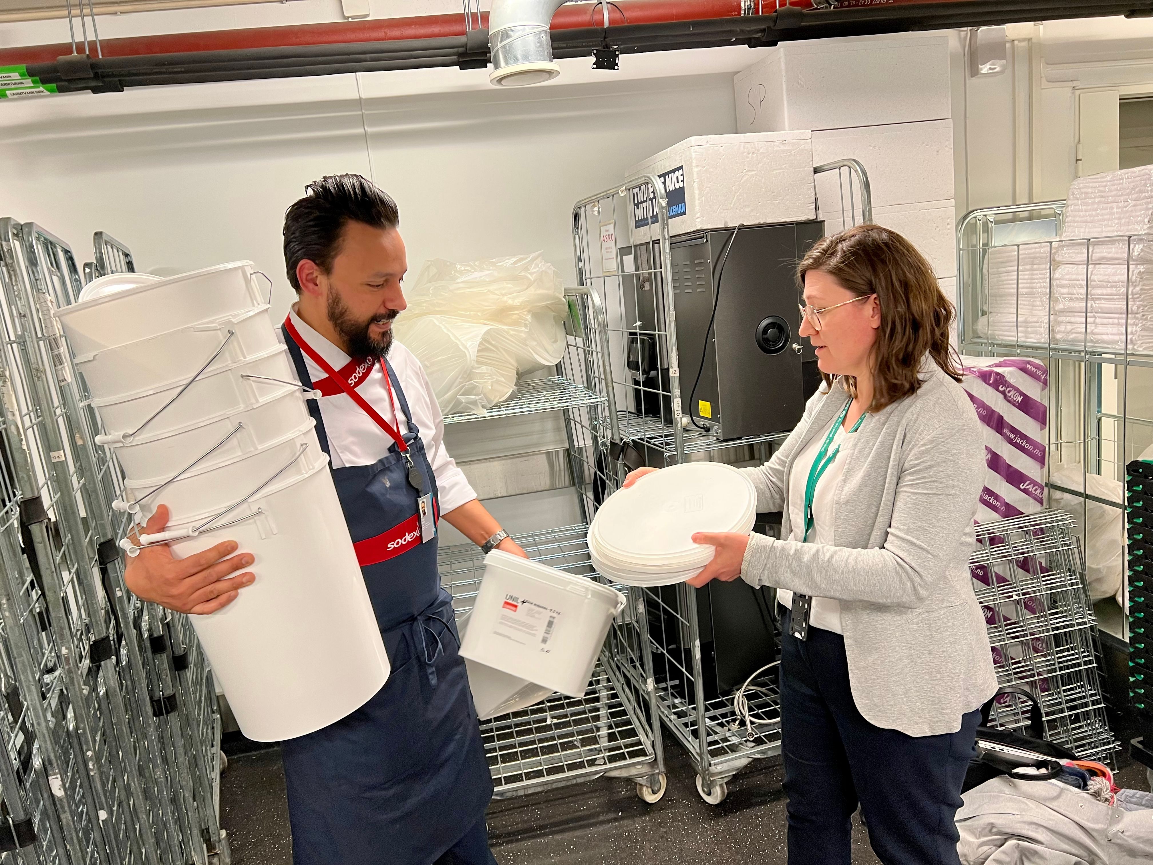 Diego Madoz from Sodexo and Dr. Susie Jahren from AION looking at empty plastic buckets.